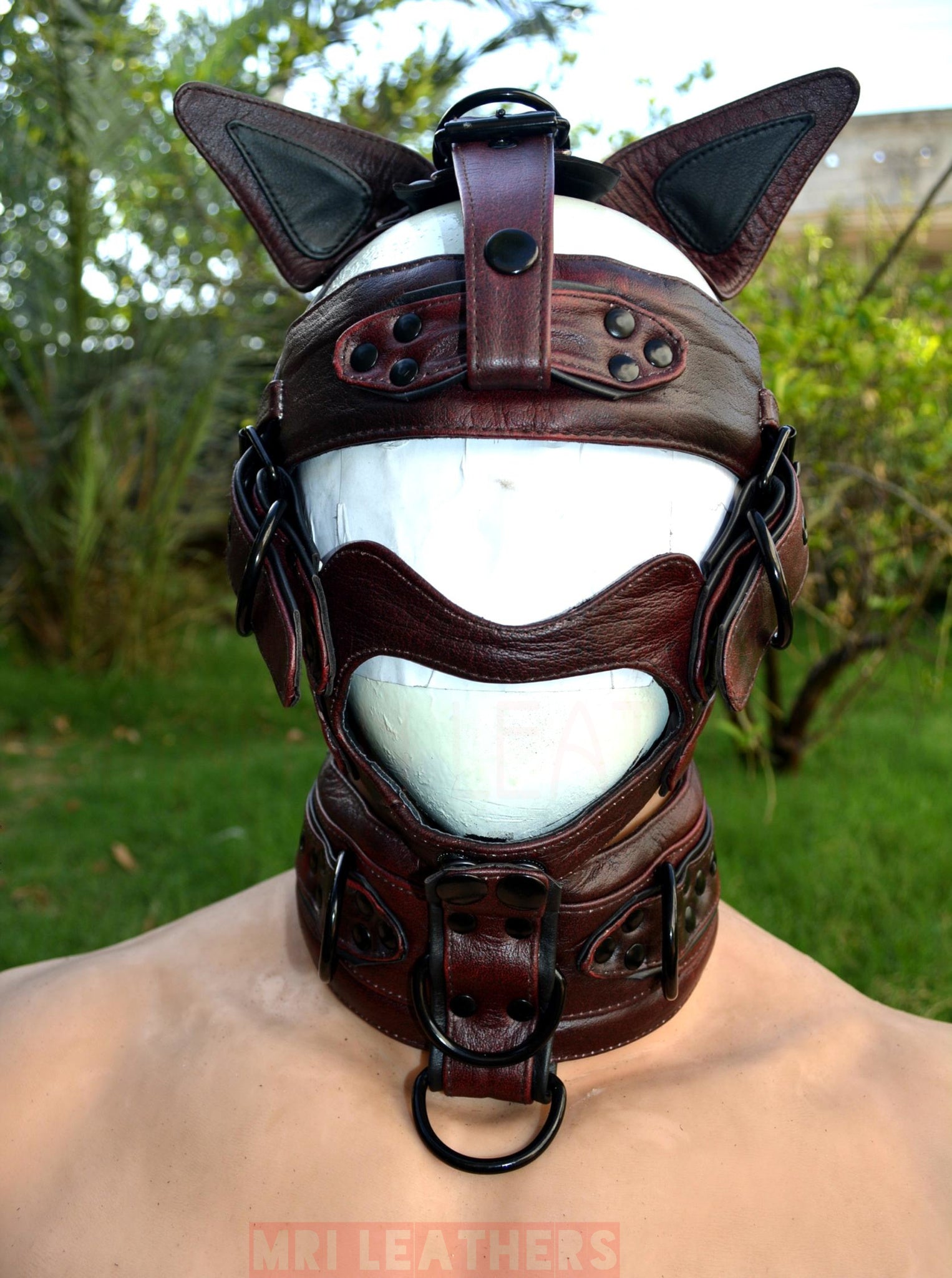 Black leather dog muzzle hood with spikes and brass hardware, adjustable for puppy play.
