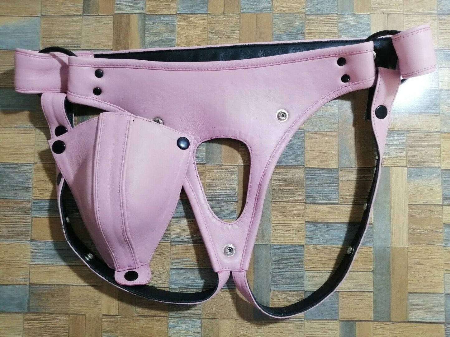 Men pink leather jock strap with removable pouch and back closure on wooden surface